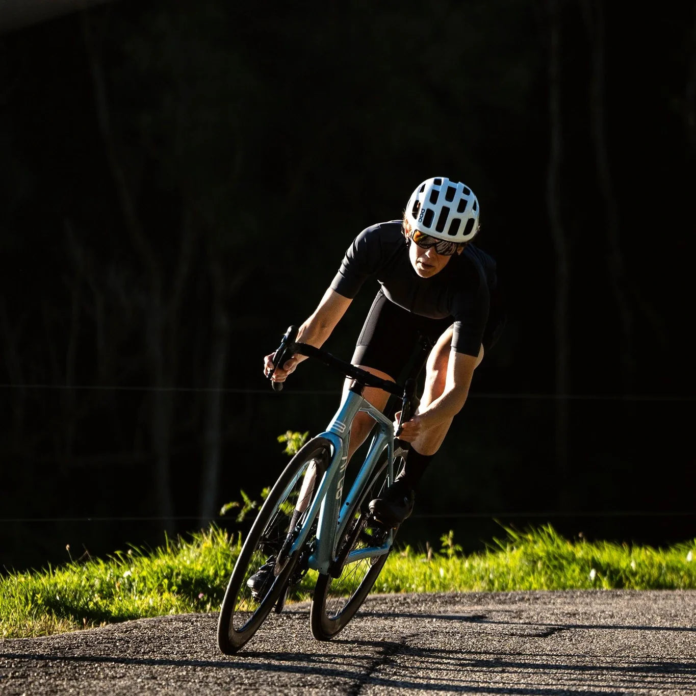 A person cycling on an ARC8 Escapee at dusk with a forest in the background. The bike is Mettalic Ice Blue