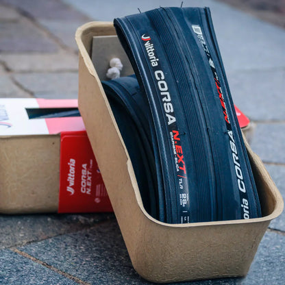 Vittoria Corsa N-Ext bicycle tires in a cardboard box on a pavement.